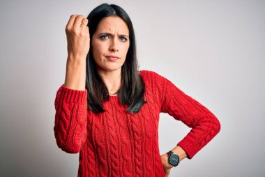 Mavi gözlü genç esmer kadın izole edilmiş beyaz arka planda günlük süveter giyiyor. İtalyan jestleri yapıyor. El ve parmakları kendinden emin ifade ediyor.