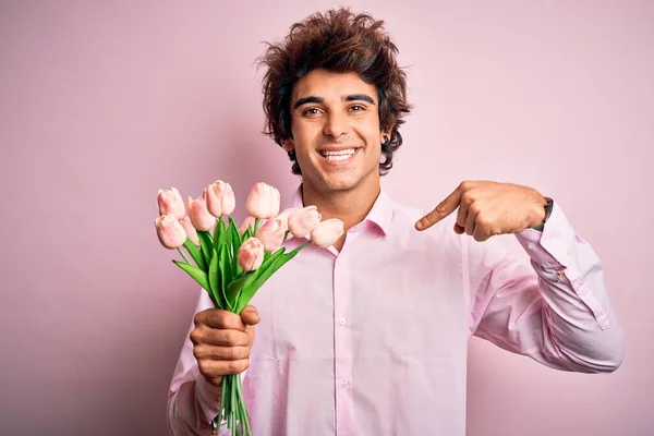Mladý Pohledný Muž Drží Květiny Stojící Nad Izolované Růžové Pozadí — Stock fotografie