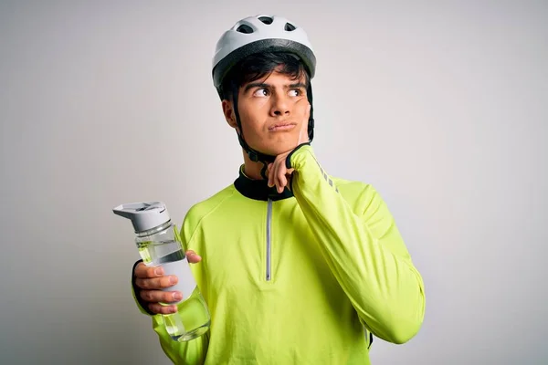 年轻英俊的骑自行车的男人戴着安全帽 喝着一瓶水 严肃地思考着问题 非常迷惑的想法 — 图库照片