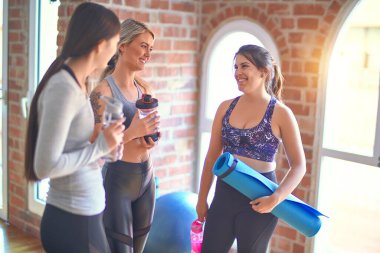 Mutlu gülümseyen genç ve güzel bir spor kadını grubu. Beden dersinden sonra yüzünde gülümsemeyle ayakta dikilip konuşmak.