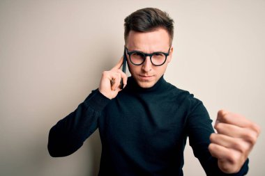 Yakışıklı, beyaz bir adam akıllı telefondan konuşuyor sinirlenmiş ve sinirlenmiş bir şekilde bağırıyor, çıldırmış ve el kaldırarak bağırıyor.