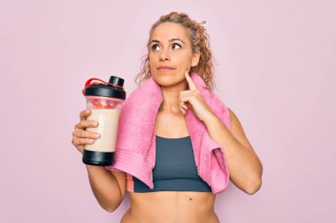 Güzel, sarışın, spor yapan, havluyla sallanan, protein içeceği taşıyan, spor yapan, ciddi yüzlü, eli çenesinde soru soran, kafa karıştırıcı bir kadın.