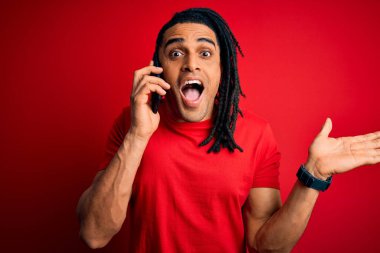 Afrika kökenli Afro Amerikalı genç adam Rastalı telefonuyla konuşuyor. Çok mutlu ve heyecanlı, kazanan yüz ifadesi zaferi büyük bir gülümsemeyle kutluyor ve ellerini kaldırıyor.