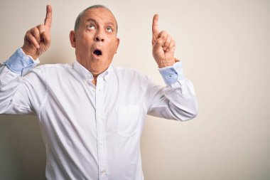 Üst düzey yakışıklı iş adamı zarif gömleğini giyer. Pembe arka plan üzerinde durur. Şaşırır ve şaşırır..