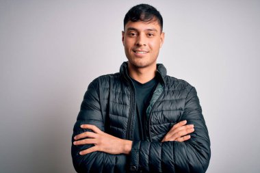 Beyaz izole edilmiş arka planda duran, kollarını kavuşturup kameraya gülümseyen, kışlık palto giyen genç, yakışıklı İspanyol adam. Pozitif kişi.
