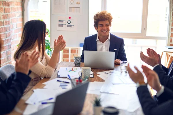 Group of business workers smiling happy and confident in a meeting. Working together looking at presentation using board and laptop applauding at the office.