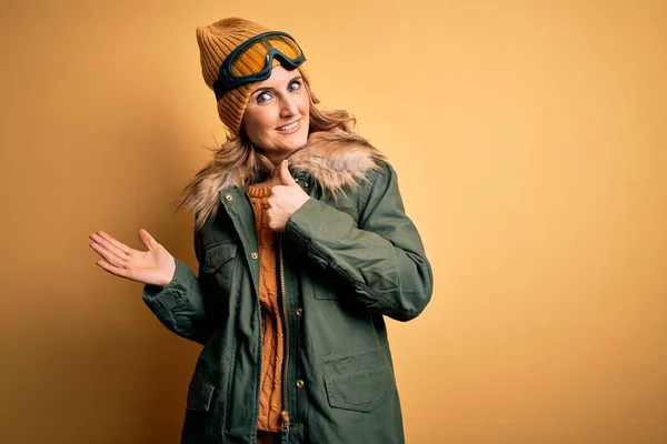 中世美しいですブロンドスキーヤー女性身に着けています雪のスポーツウェアとスキーゴーグル手のひら手を表示し 指でOkジェスチャーを行いますアップ 笑顔と陽気な — ストック写真