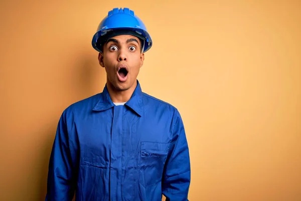 年轻英俊的非洲工人 身穿蓝色制服 头戴安全帽 脸上带着惊讶的表情 恐惧和兴奋的表情 感到害怕和震惊 — 图库照片