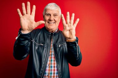 Kıdemli yakışıklı, beyaz gömlekli ve ceketli adam izole edilmiş kırmızı arka planda dokuz numarayı gösteriyor ve gülümserken kendinden emin ve mutlu görünüyor..