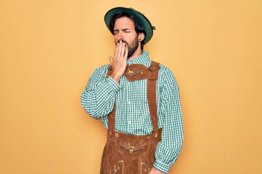 Almanya festivali için geleneksel Alman Ekim Festivali kıyafeti giyen genç yakışıklı adam, ağzıyla ağzını kapatmaktan sıkıldı. Huzursuz ve uykulu..