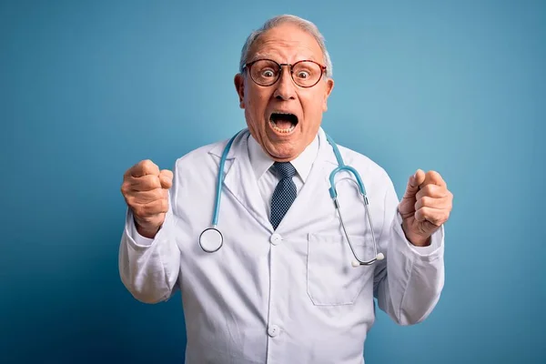 Starszy Siwy Lekarz Noszący Stetoskop Płaszcz Medyczny Niebieskim Tle Świętujący — Zdjęcie stockowe