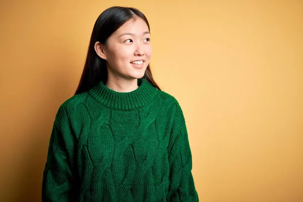 녹색의 스웨터를 노랗게 위에서 웃으며 바라보고 아름다운 아시아 여인은 스러운 — 스톡 사진