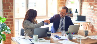 Mutlu ve kendinden emin gülümseyen iki orta yaşlı iş adamı. Yüzünde gülümsemeyle çalışmak ofiste yumruk tokuşturmak.