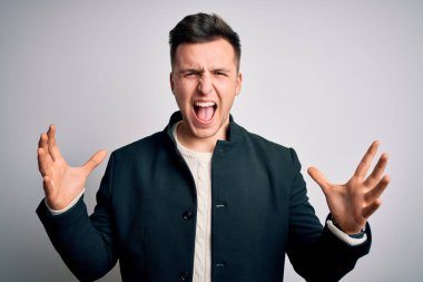 Zarif bir kışlık ceket giyen genç yakışıklı iş adamları izole arka planda çılgın ve kızgın bir şekilde bağırıyor ve agresif bir ifade ve kolla bağırıyor. Hayal kırıklığı konsepti.