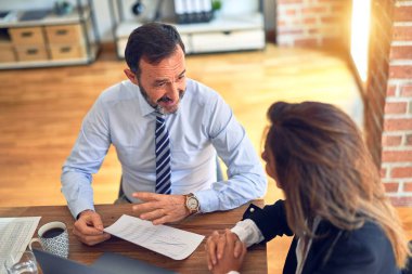 Mutlu ve kendinden emin gülümseyen iki orta yaşlı iş adamı. Ofiste dizüstü bilgisayarla gülümseyerek birlikte çalışıyoruz.