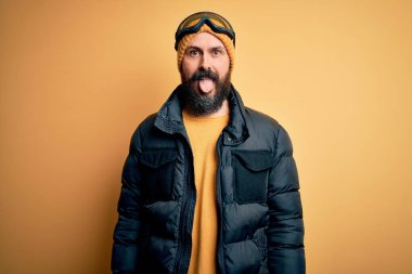 Sakallı, kar maskesi takmış, kar maskesi takmış, kel yakışıklı kayakçı komik bir ifadeyle dilini dışarı çıkarmış. Duygu kavramı.