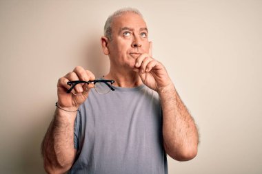 Orta yaşlı, beyaz arka planda görüş gözlüğü takan beyaz bir adam soru soran, kafası karışık bir fikir düşünen ciddi bir yüz.