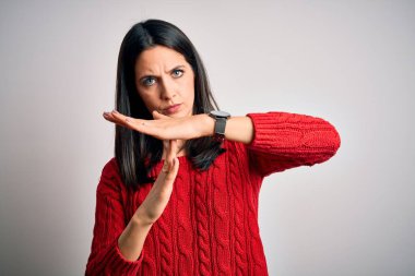 Mavi gözlü genç esmer kadın izole edilmiş beyaz arka plan üzerine günlük süveter giyiyor. Elleriyle jest yapıyor, hayal kırıklığına uğramış ve ciddi bir yüz ifadesi var.