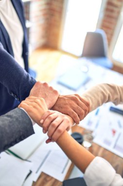 Bir grup işçi el ele tutuşup ofiste sembol oluşturuyorlar.