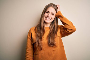 Genç, güzel, kızıl saçlı bir kadın izole edilmiş beyaz bir arka plan üzerine gündelik kazak giyip soru sormayı merak ediyor. Şüpheyle kararsız, kafa kafaya düşünerek. Düşünceli kavram.