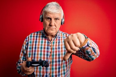 Kıdemli yakışıklı, ağdalı oyuncu oyun oynuyor. Oyun çubuğu ve kulaklık kullanıyor. Kızgın yüzlü, negatif işaretli, baş parmakları aşağıda, reddedilme kavramından hoşlanmadığını gösteriyor.
