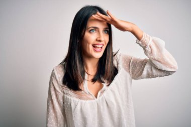 Mavi gözlü genç esmer kadın izole edilmiş beyaz arka plan üzerine gündelik tişört giyiyor çok mutlu ve tebessüm ediyor. Konsept aranıyor.