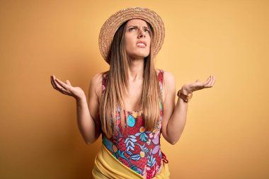 Sarı arka planda mayo ve yaz şapkası takan genç, güzel, sarışın bir kadın. Deli gibi bağırıyor, agresif bir ifadeyle bağırıyor ve kollarını kaldırıyor. Hayal kırıklığı konsepti.