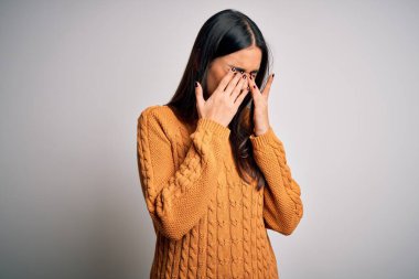 Genç, güzel esmer kadın izole edilmiş beyaz arka plan üzerine gündelik bir kazak giyiyor yorgunluk ve baş ağrısı için gözlerini ovuşturuyor, uykulu ve yorgun bir ifade takınıyor. Görüş sorunu