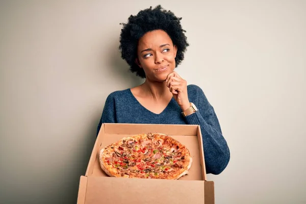 若いですアフリカ系アメリカ人アフロ女性とともに巻き毛保持デリバリーボックスでイタリアのピザ深刻な顔を考えます質問について 非常に混乱したアイデア — ストック写真