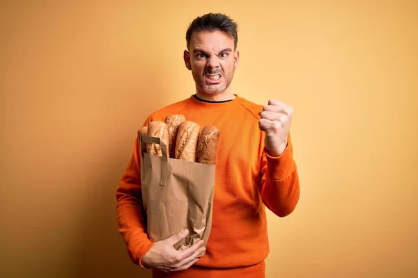 Sarı Arka Planda Ekmeği Olan Genç Yakışıklı Bir Adam Öfkeyle — Stok fotoğraf
