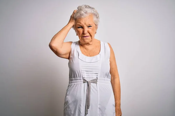 Senior beautiful grey-haired woman wearing casual summer dress over white background confuse and wonder about question. Uncertain with doubt, thinking with hand on head. Pensive concept.