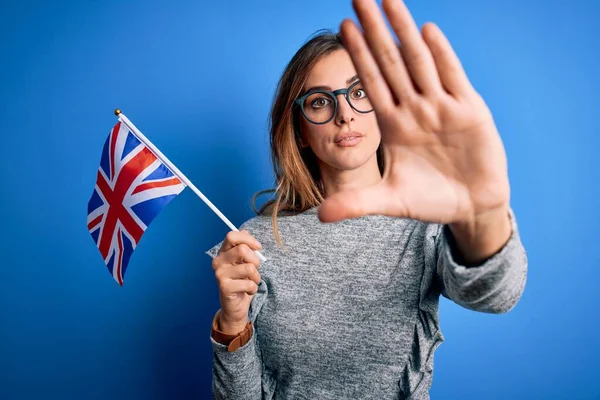 若いです美しいですブルネット愛国的な女性を保持しています英国のフラグ上の出口投票でオープン手を行います停止標識で真剣で自信を持って式 防衛ジェスチャー — ストック写真