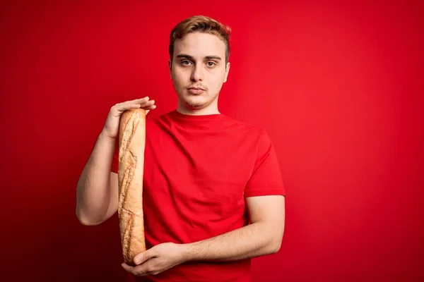 Young Handsome Redhead Man Holding Fresh Homemade Bread Isolated Red — Stock Photo, Image