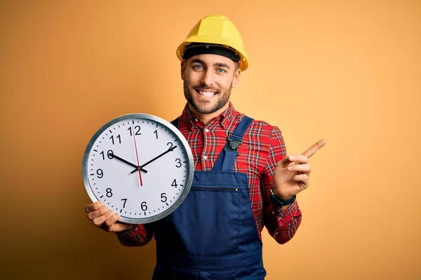 Young Builder Man Wearing Safety Helmet Holding Big Clock Yellow — Stock Photo, Image