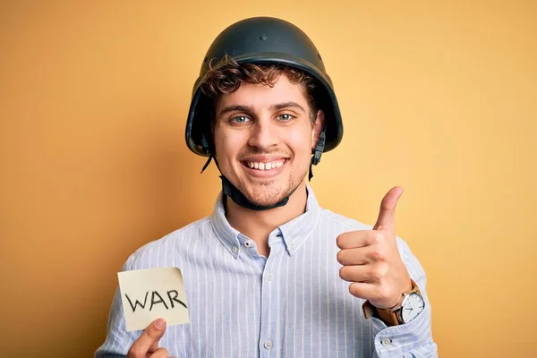 若いですブロンドビジネスマンとともに巻き毛ヘルメット保持紙で戦争メッセージ幸せなで大きな笑顔を行いますOkサイン 指で親指アップ 優れたサイン — ストック写真