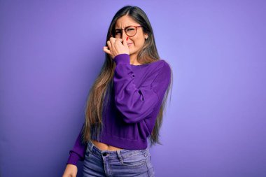 Genç, güzel, zeki bir kadın mor arka planda gözlük takıyor. Kokuşmuş ve iğrenç bir koku alıyor. Dayanılmaz bir koku. Kötü kokuyor.