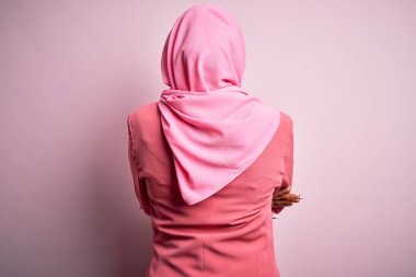 Genç Afrikalı Afro kadın, izole edilmiş pembe arka plan üzerine Müslüman başörtüsü takmış geriye doğru çapraz kollarla bakıyor.