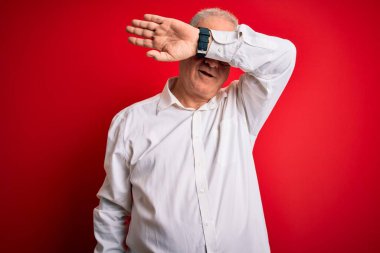 Orta yaşlı yakışıklı, beyaz gömlekli, gözlüklü, kırmızı arka planda gözlüklü, neşeli ve komik kollu bir adam. Kör kavram.