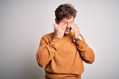 Sarışın, kıvırcık saçlı, beyaz arka planda rahat süveter giyen, yorgun ve uykulu bir ifade takınan genç, yakışıklı bir adam. Görüş sorunu 