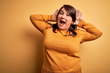 Güzel esmer ve cüsseli bir kadın izole edilmiş sarı arka planda günlük süveter giyiyor neşeli gülümsüyor ve elleriyle bir böceği dikizliyor. Şaşırdım ve çıktım.