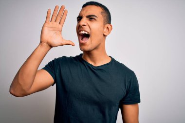 Beyaz arka planda durup el ele tutuşarak bağıran, sıradan tişörtler giyen genç ve yakışıklı Afro-Amerikalı adam. İletişim konsepti.