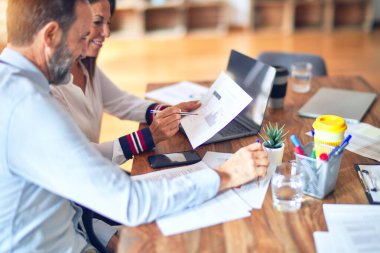 Mutlu ve kendinden emin gülümseyen iki orta yaşlı iş adamı. Ofiste dizüstü bilgisayarla gülümseyerek birlikte çalışıyoruz.