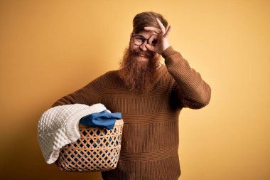 Kızıl saçlı, sakallı, sarı arka planda ev işi yapan, gülümseyen, el pençe divan duran, el pençe divan duran İrlandalı adam.