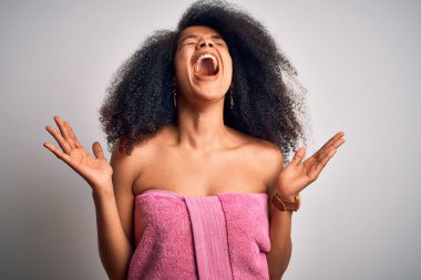 Afro saçlı Afrikalı genç bir kadın güzellik öncesi duştan sonra vücut havlusu takıyor ve başarıya deli gibi seviniyor kollarını kaldırmış ve gözlerini kapamış heyecanla haykırıyor. Kazanan konsept