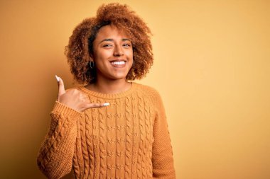 Kıvırcık saçlı, sıradan bir süveter giyen, el ve parmaklarıyla telefonla konuşan güzel Afro-Amerikan bir kadın. İletişim kavramları.