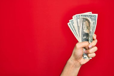 Güzel bir el, kırmızı arka planda bir deste dolar tutan bir adam.