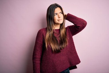 Soyutlanmış pembe arka plan karışıklığı üzerine sıradan süveter giyen genç ve güzel bir kız soru sormayı merak ediyor. Şüpheyle kararsız, kafa kafaya düşünerek. Düşünceli kavram.