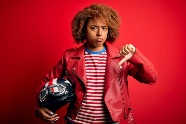 若いアフリカ系アメリカ人のオートバイのヘルメットを持っている女性上の赤い背景で怒っている顔 否定的な兆候を示す嫌悪で親指ダウン 拒絶概念 — ストック写真