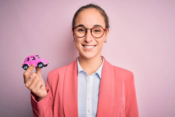 Νεαρή Όμορφη Επιχειρηματίας Φορώντας Γυαλιά Κρατώντας Ροζ Αυτοκίνητο Παιχνίδι Απομονωμένο — Φωτογραφία Αρχείου