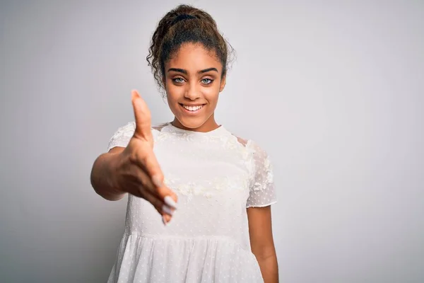 白い背景の上に立つカジュアルなTシャツを着た若い美しいアフリカ系アメリカ人の女の子は 挨拶や歓迎として握手を提供しています 成功事業 — ストック写真